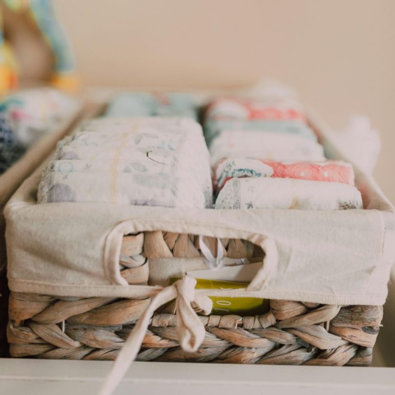 Woven basket containing neatly folded towels in various pastel colours.