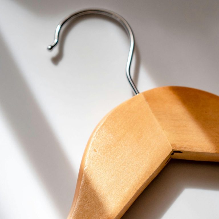 Close-up of a wooden clothes hanger with a metal hook.