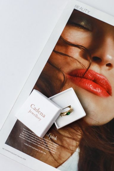 Close-up of a woman's face with red lips, featuring a ring box beside her.