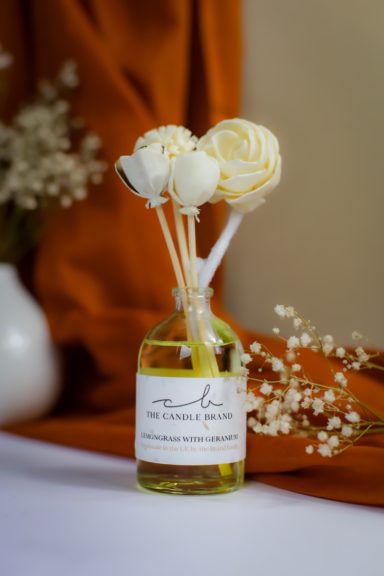 A decorative bottle with white and yellow flowers and twigs in a soft-focus background.