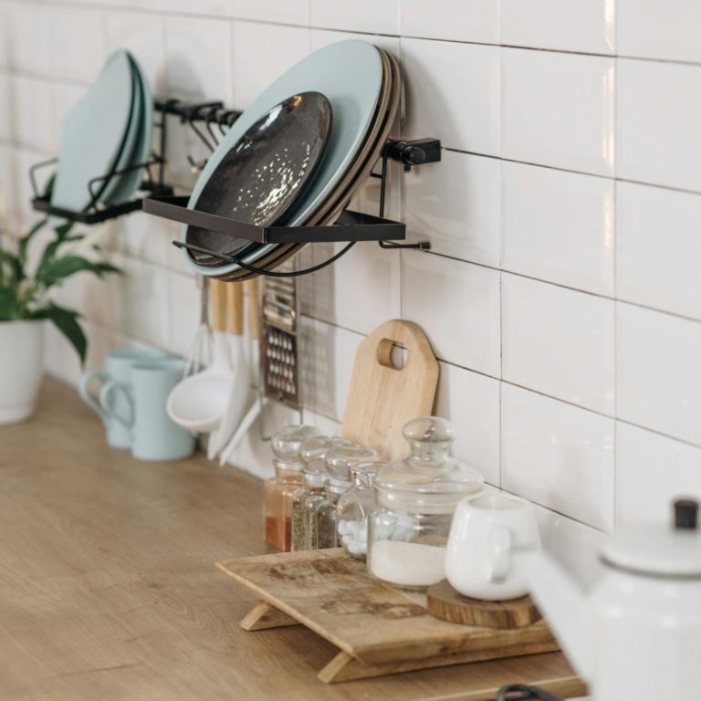 Kitchen scene featuring plates on a rack, glass containers, and plant decor.